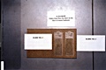 Photo depicting open slide mailer with two glass Microscope slides. Slide No. 1 marked: '90103084 - Q125 JCF MPM'; Slide No. 2 marked: 'Hair - 90103084-JCF - MPM'; and card stating: 'E-211/Q125 - Debris from blue top sheet on the floor of the master bedroom'
